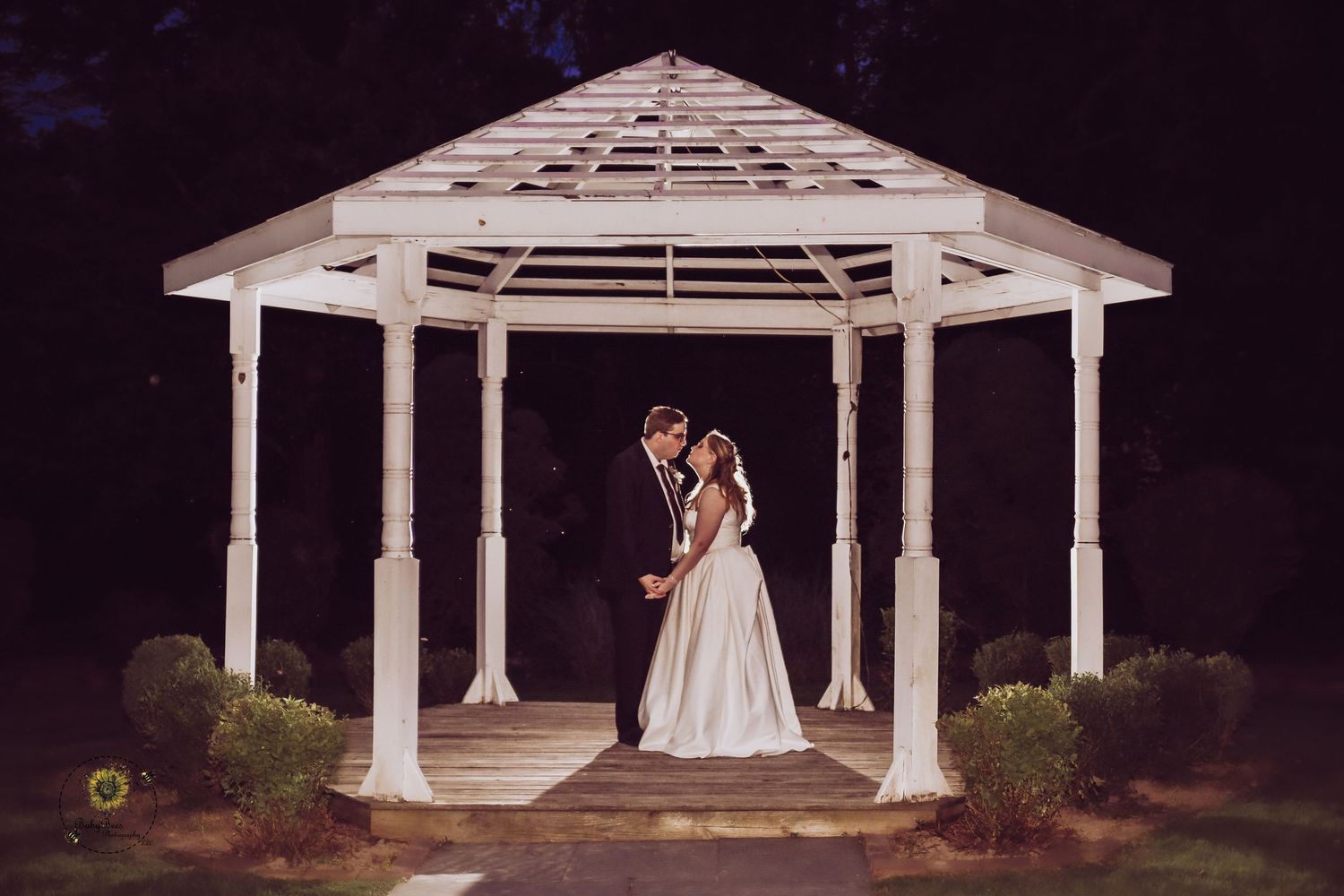 Elegant white wedding gazebo illuminated at night creating a romantic atmosphere.