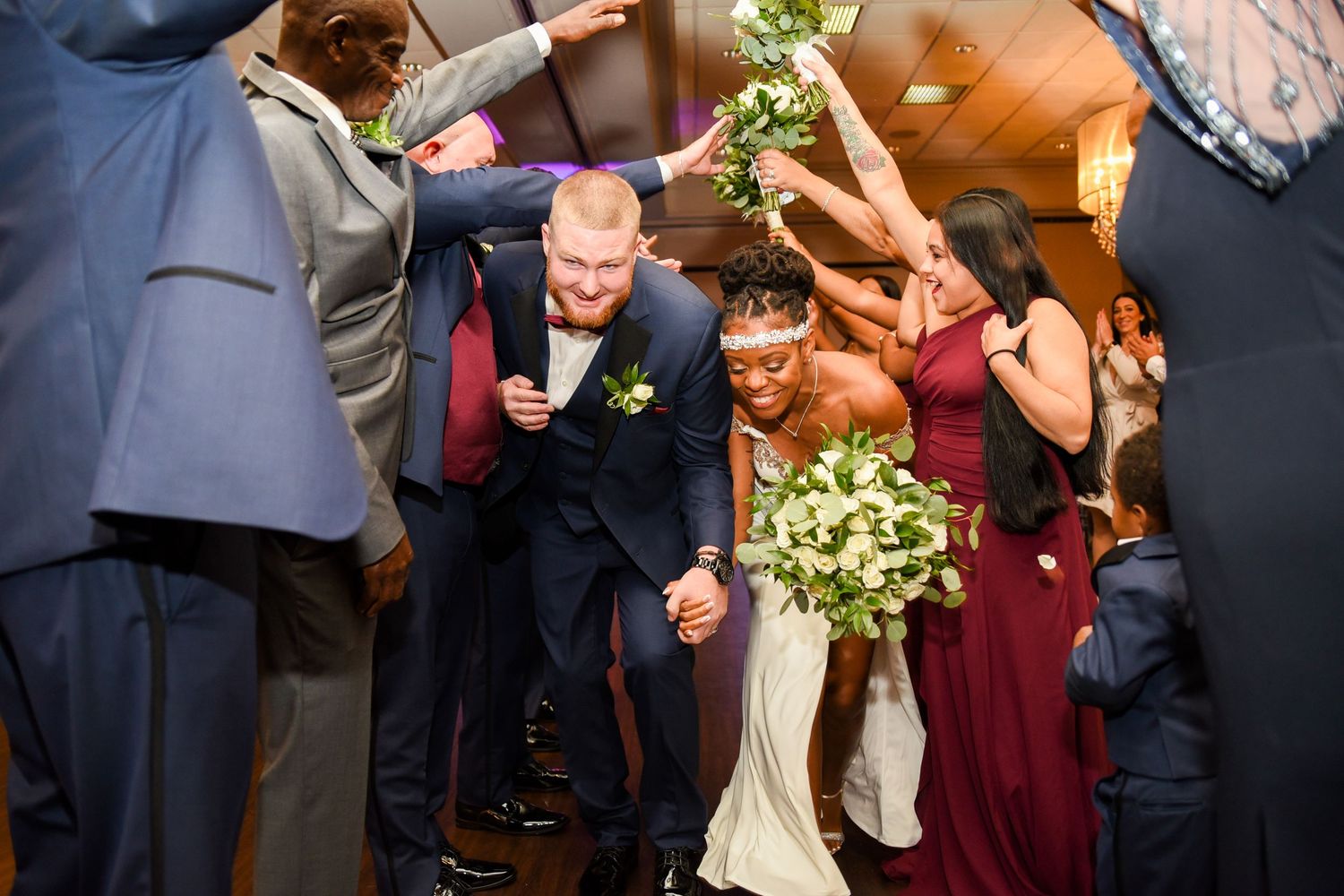 Wedding party members laugh and celebrate during a joyful group photo session.