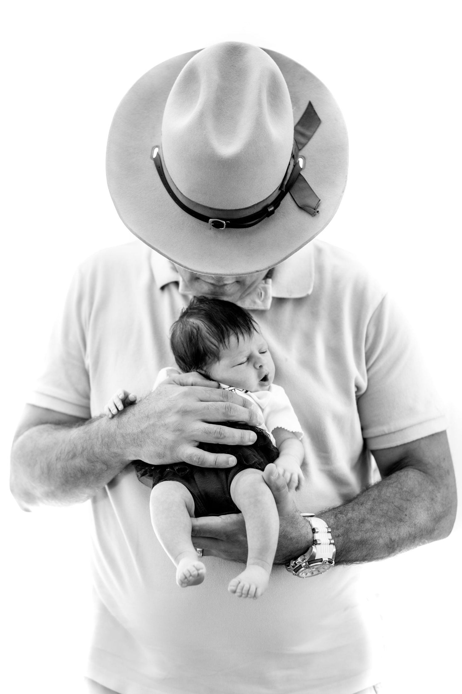 A series of black and white photos showing someone in a white shirt and hat holding a small baby in different poses.
