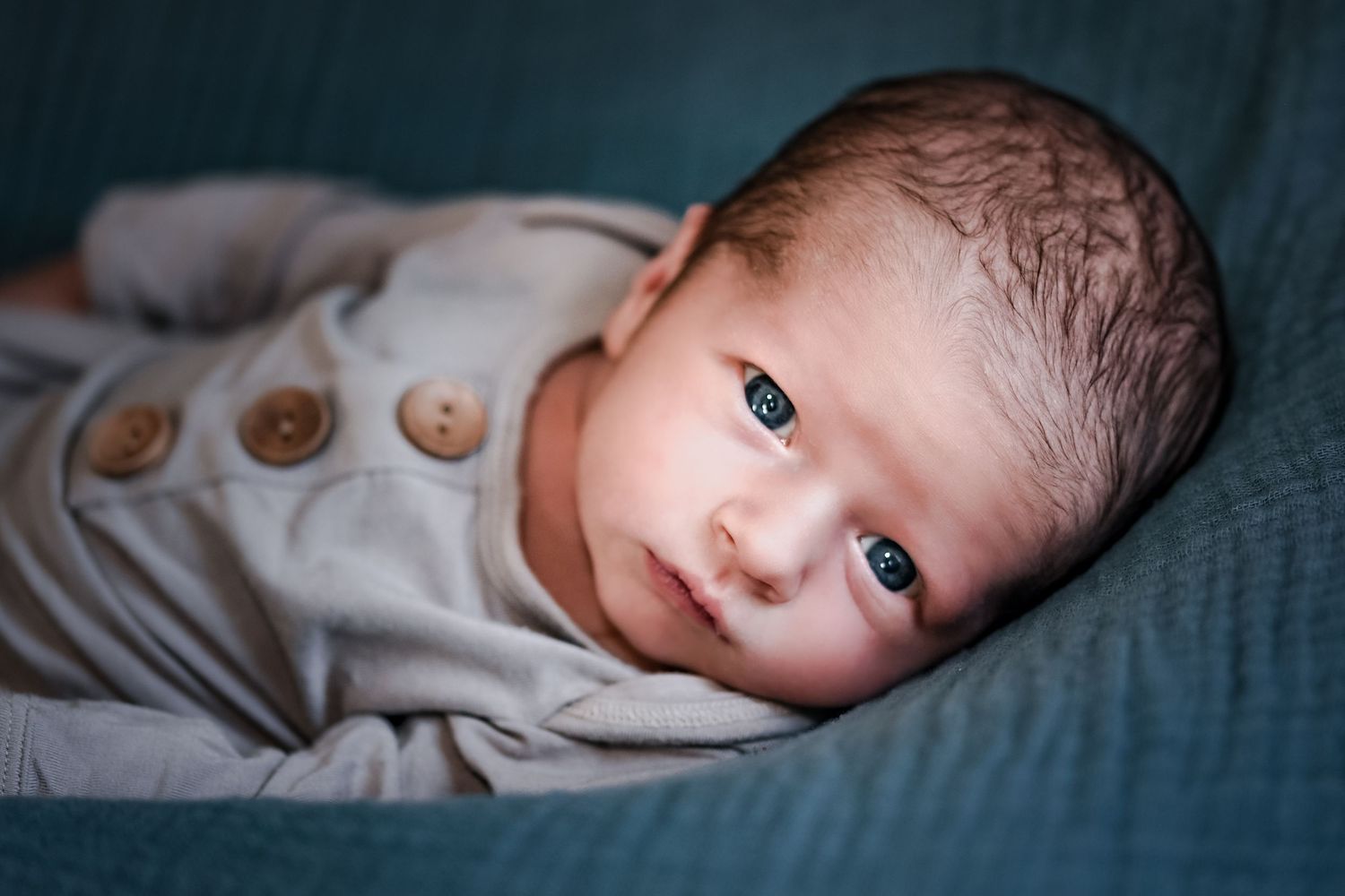 A series of close-up shots showing a newborn baby resting peacefully on soft bedding.