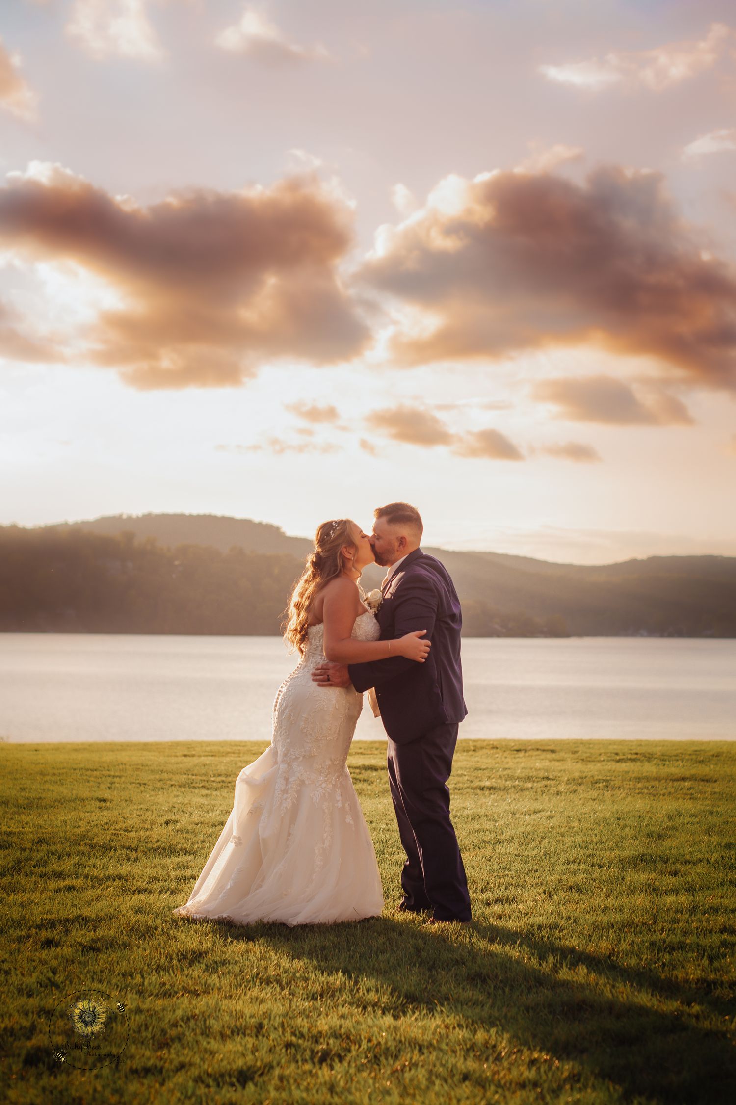 Golden sunset wedding photos in a scenic meadow by the water.