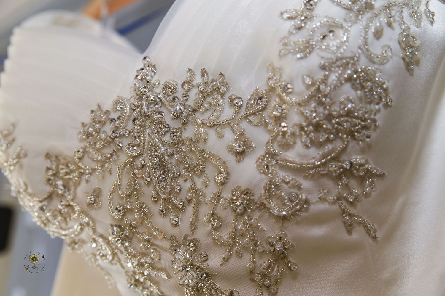 Detailed beadwork and embellishments on white wedding dress bodice.