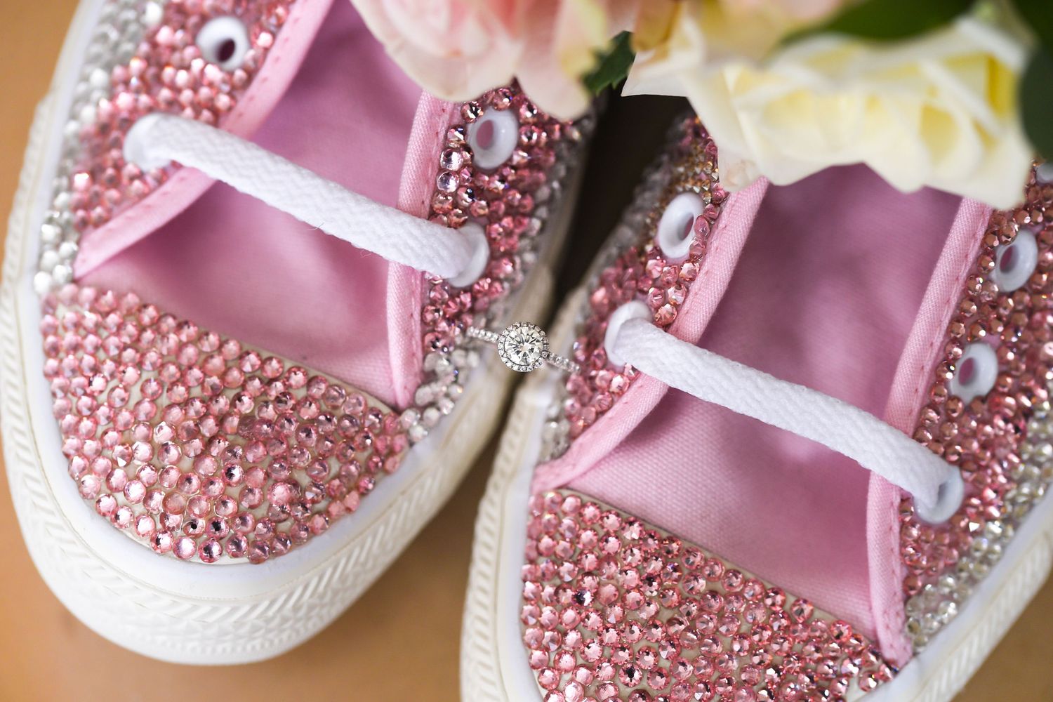 Close-up of pink rhinestone-decorated wedding sneakers with ribbon laces.