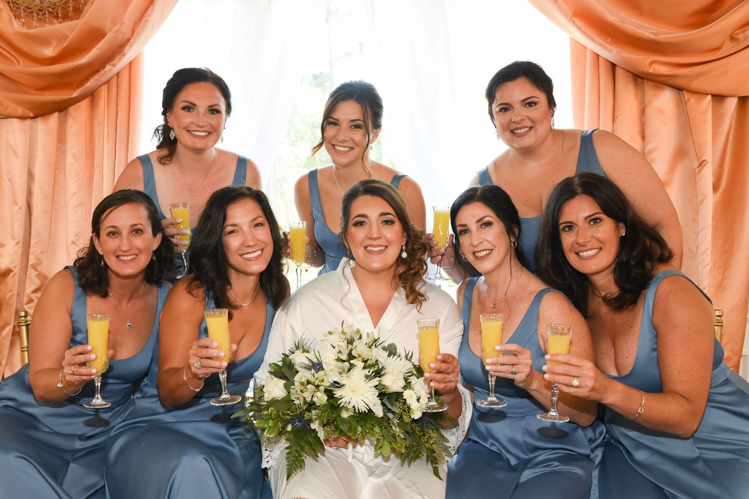 Bridesmaids in blue dresses holding champagne glasses at wedding celebration.