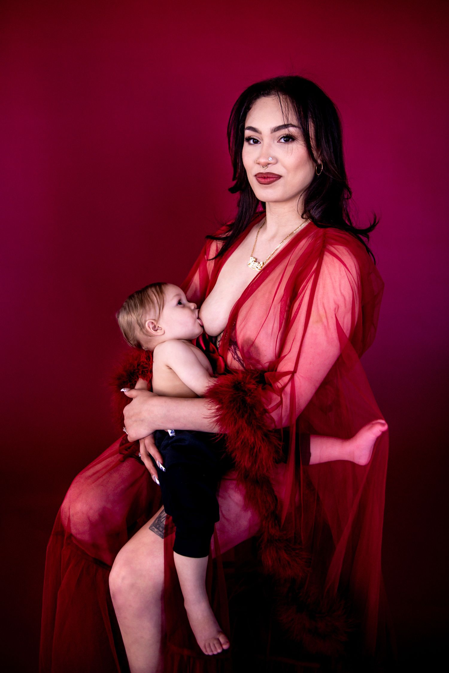 Artistic portrait series in deep red lighting showing intimate mother and baby moments against dark background.
