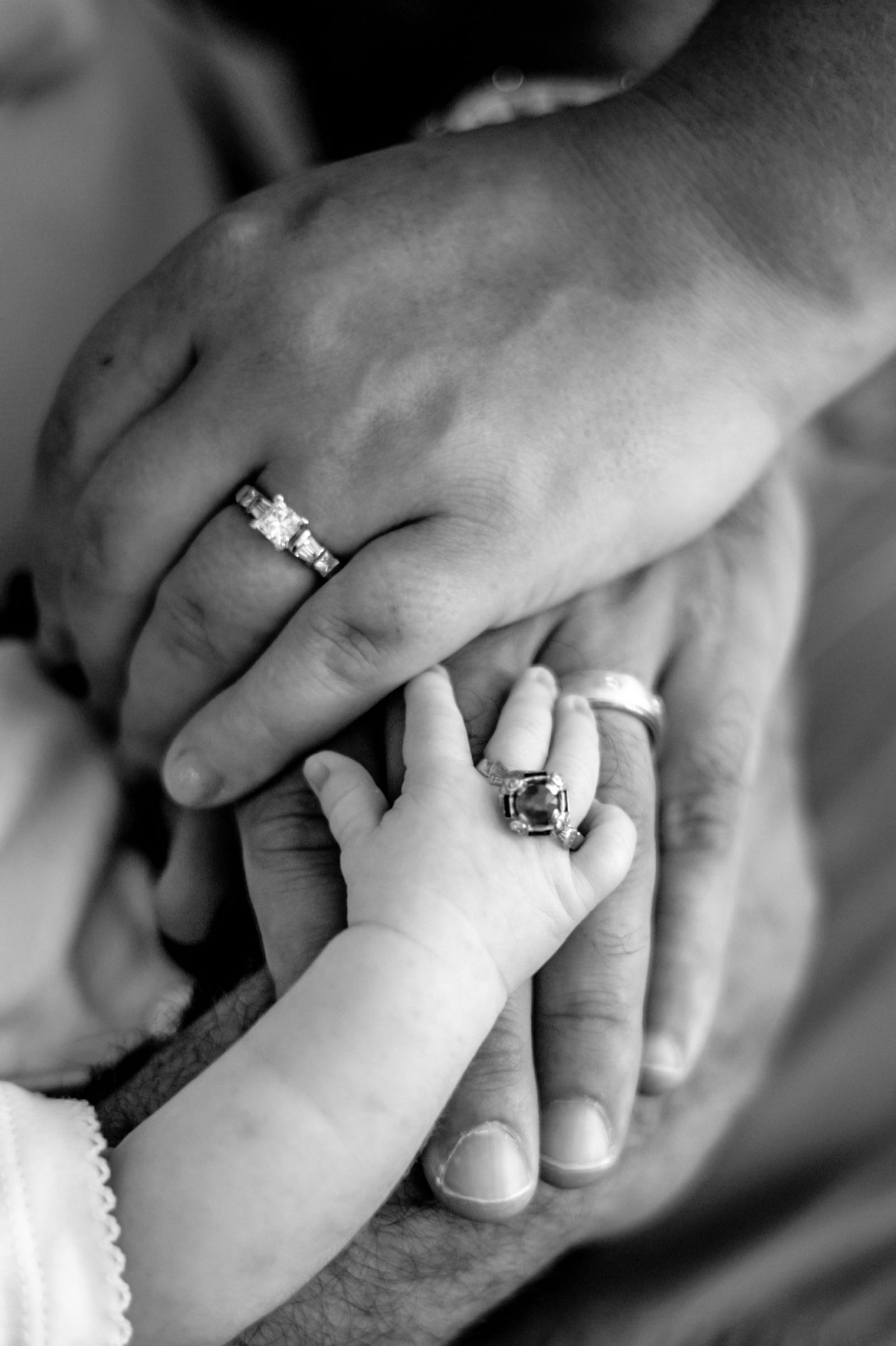 A series of black and white close-up photos showing hands wearing engagement rings and wedding bands.