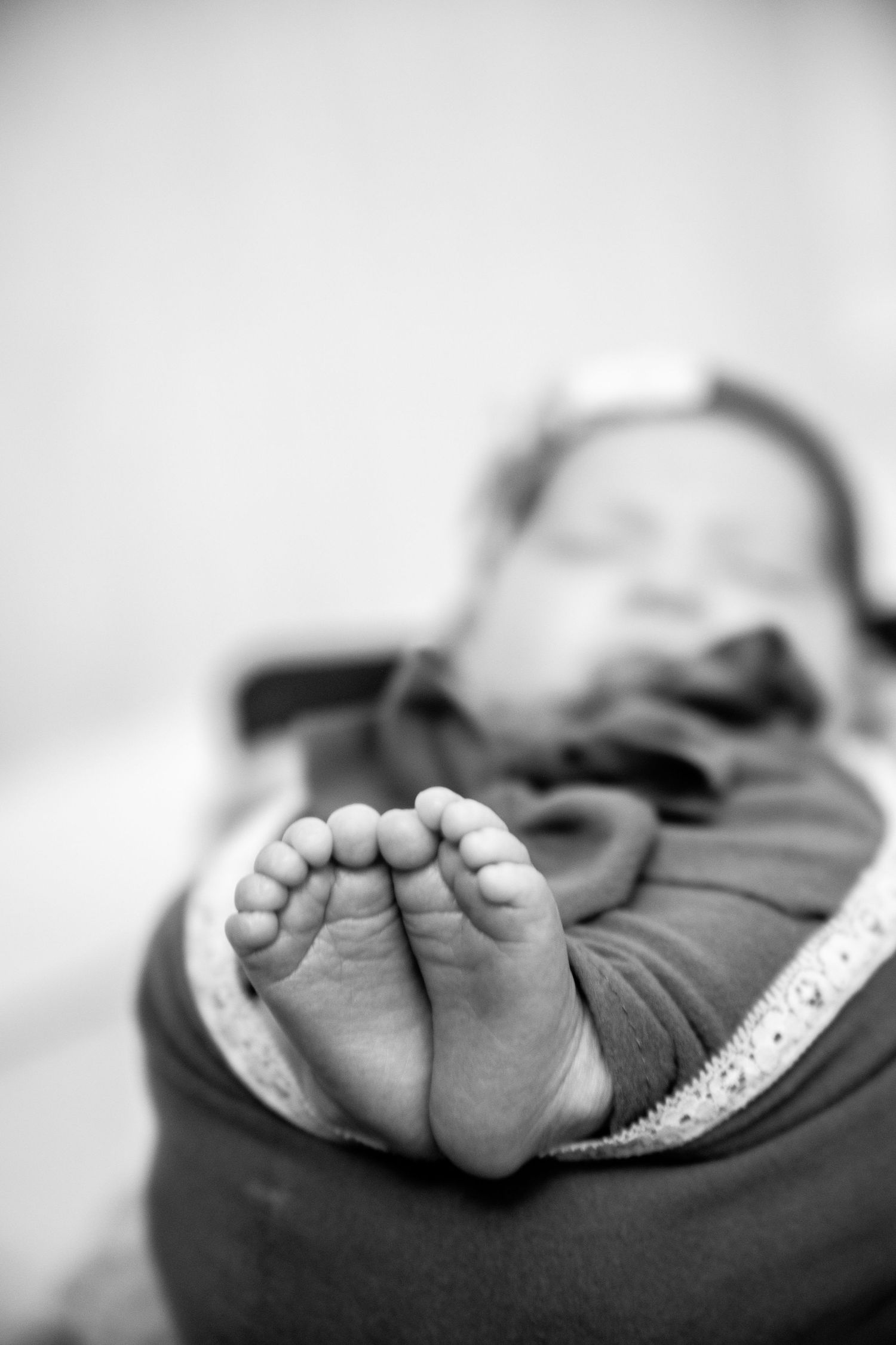 Black and white artistic series showing tiny baby feet in soft focus against a light background.