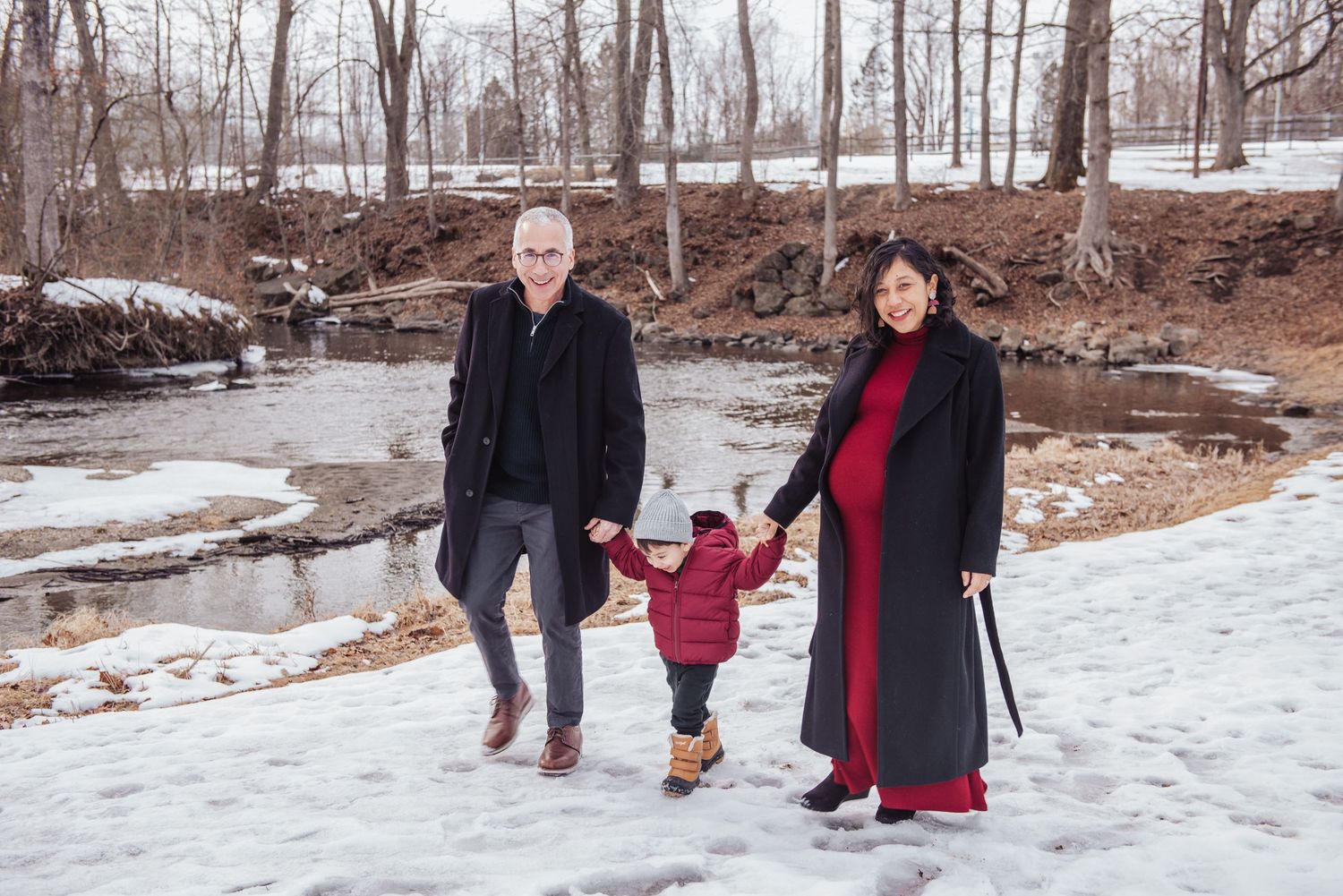 A group walks together through a snowy winter landscape in a wooded park setting.