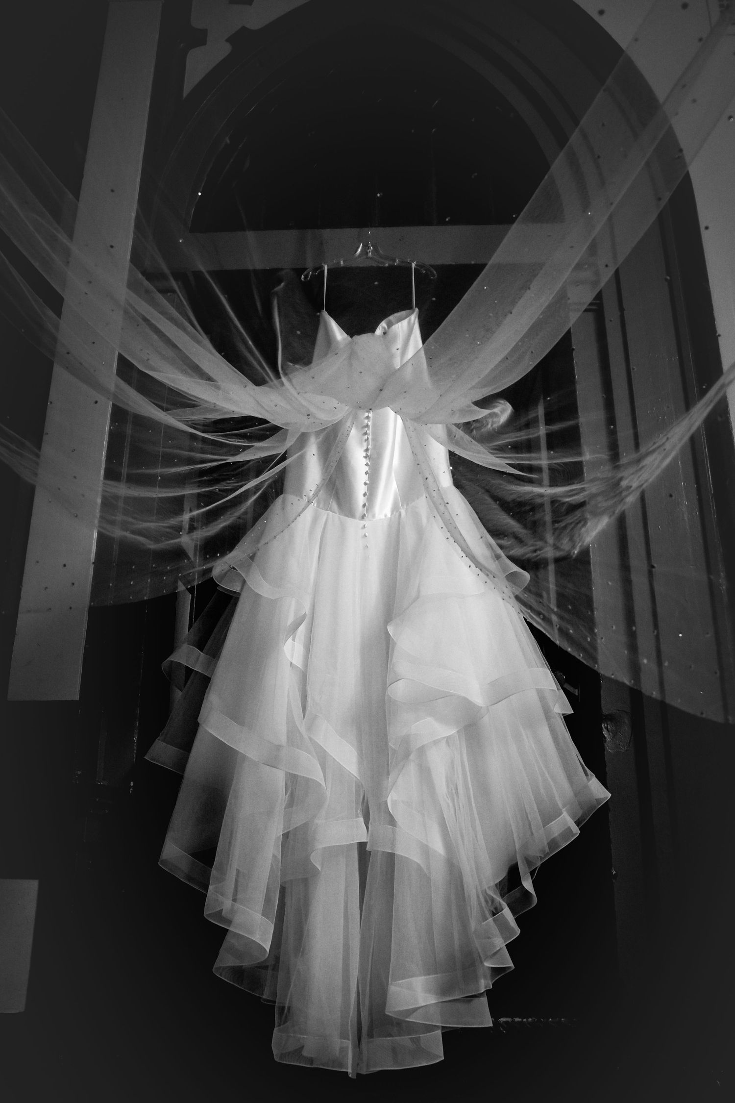 Artistic black and white photos showing the flowing layers and details of a white wedding gown.