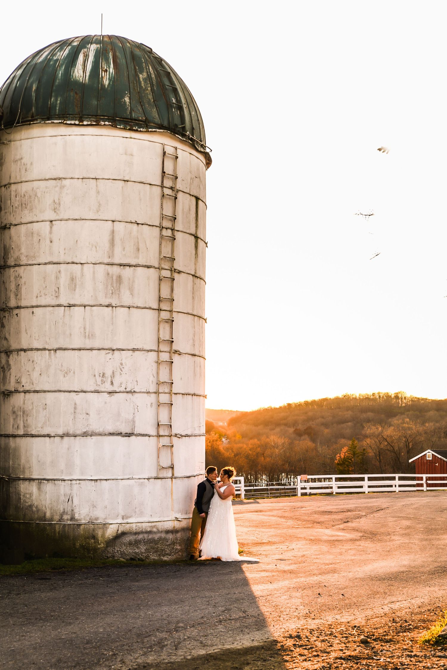 Wedding photos featuring large farm silos at sunset creating dramatic silhouettes.