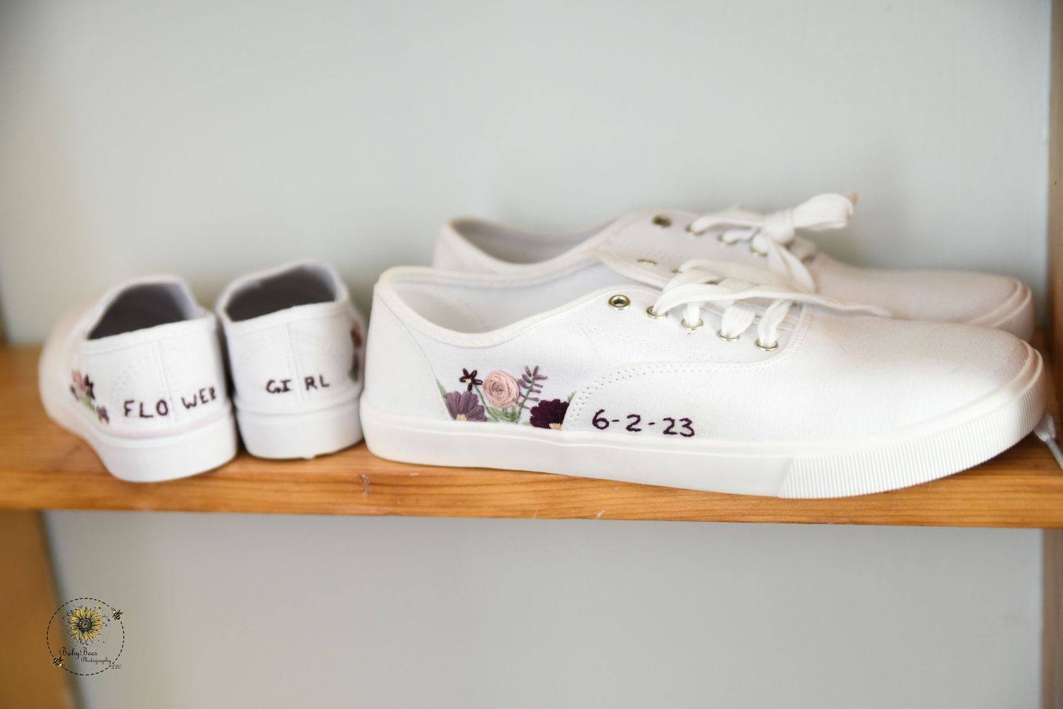White canvas wedding shoes lined up on a wooden shelf with handwritten dates.