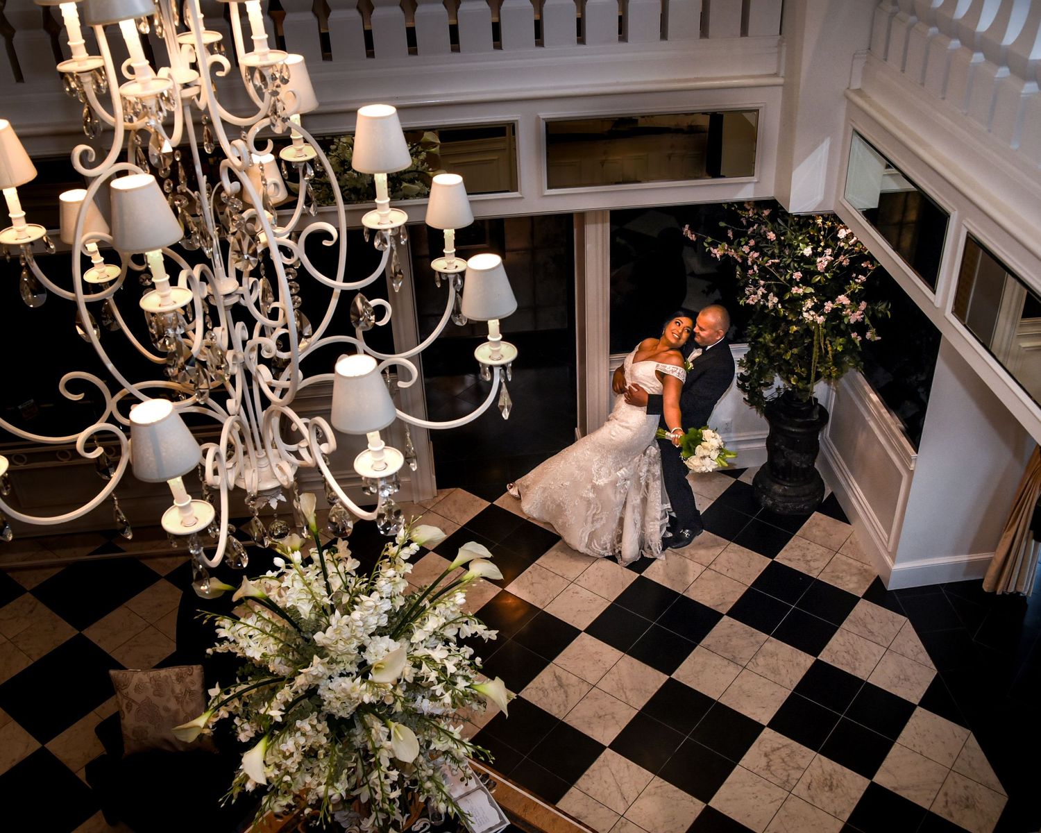 Elegant ballroom interior with black and white checkered floor and crystal chandeliers decorated for a wedding reception.