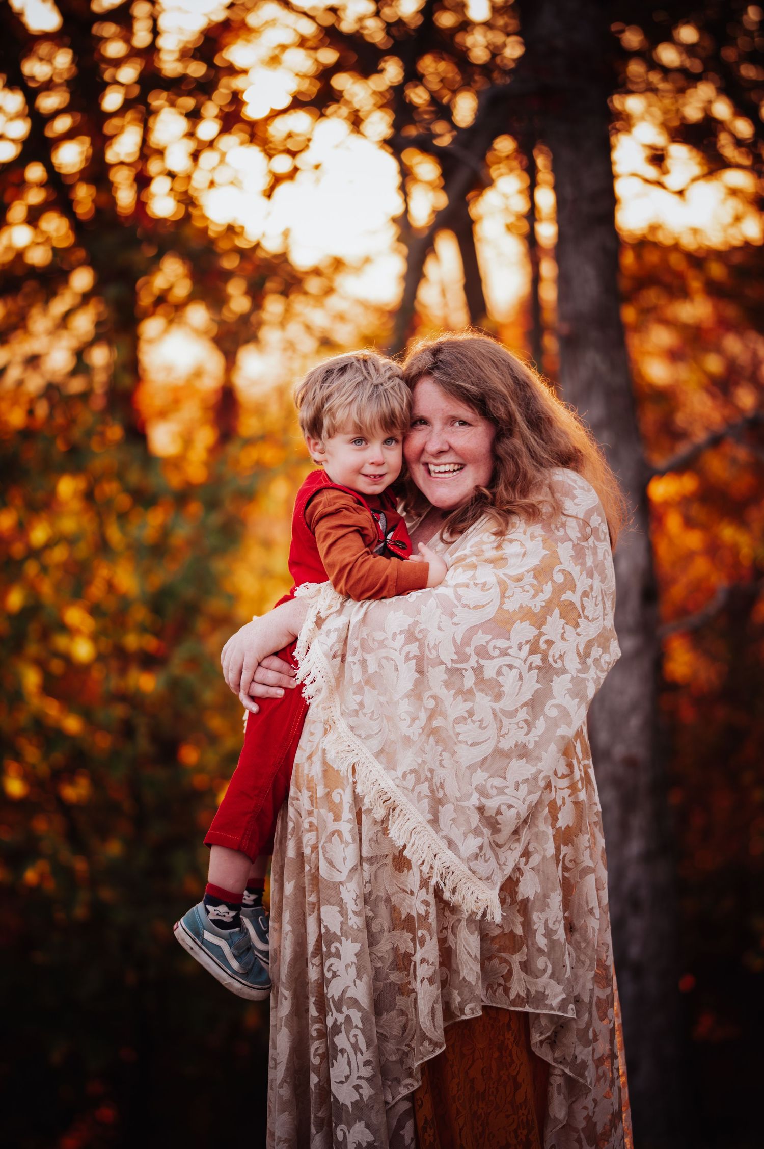 A heartwarming autumn portrait in a forest with golden bokeh lights and fall foliage in the background.