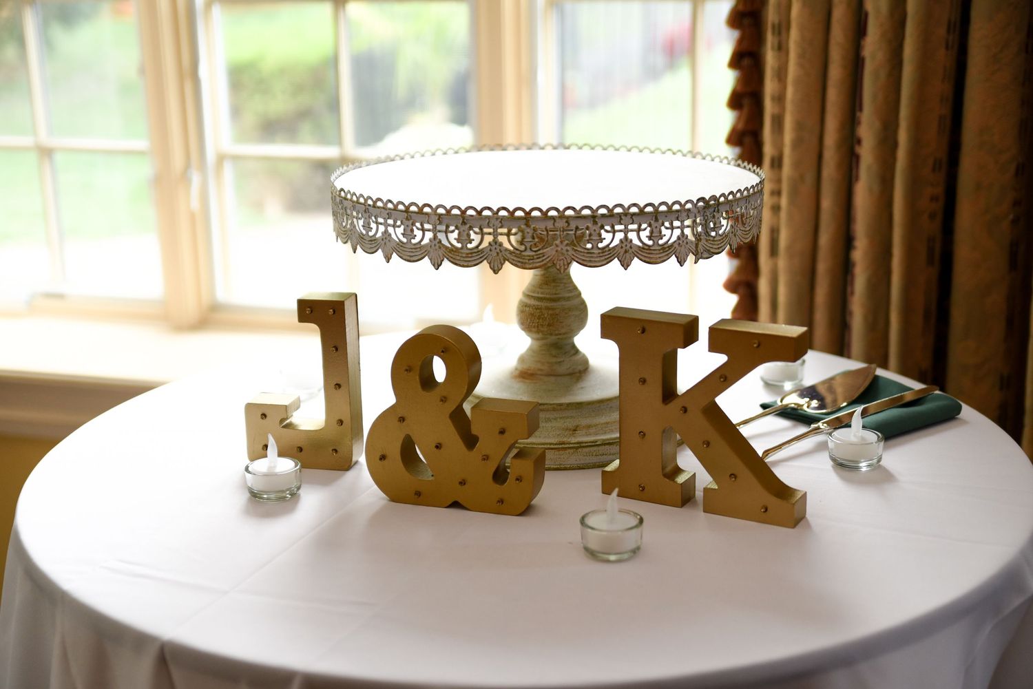 Gold decorative letters and table decor displayed on white surface near sunlit window.