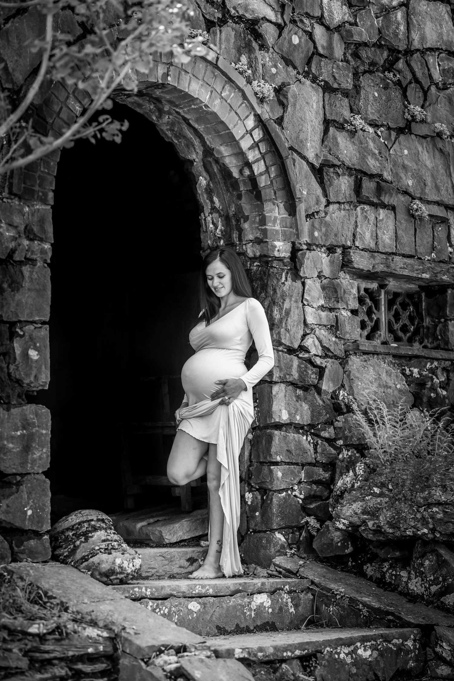 A figure in a white dress poses dramatically in a series of black and white photos against old stone archways.