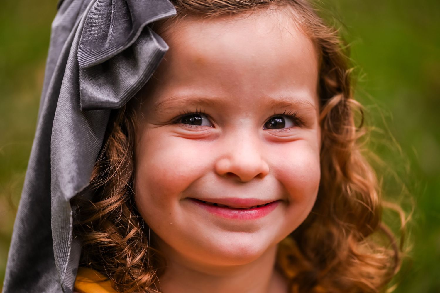 A series of four close-up portraits showing joyful expressions and curly hair against a blurred green background.