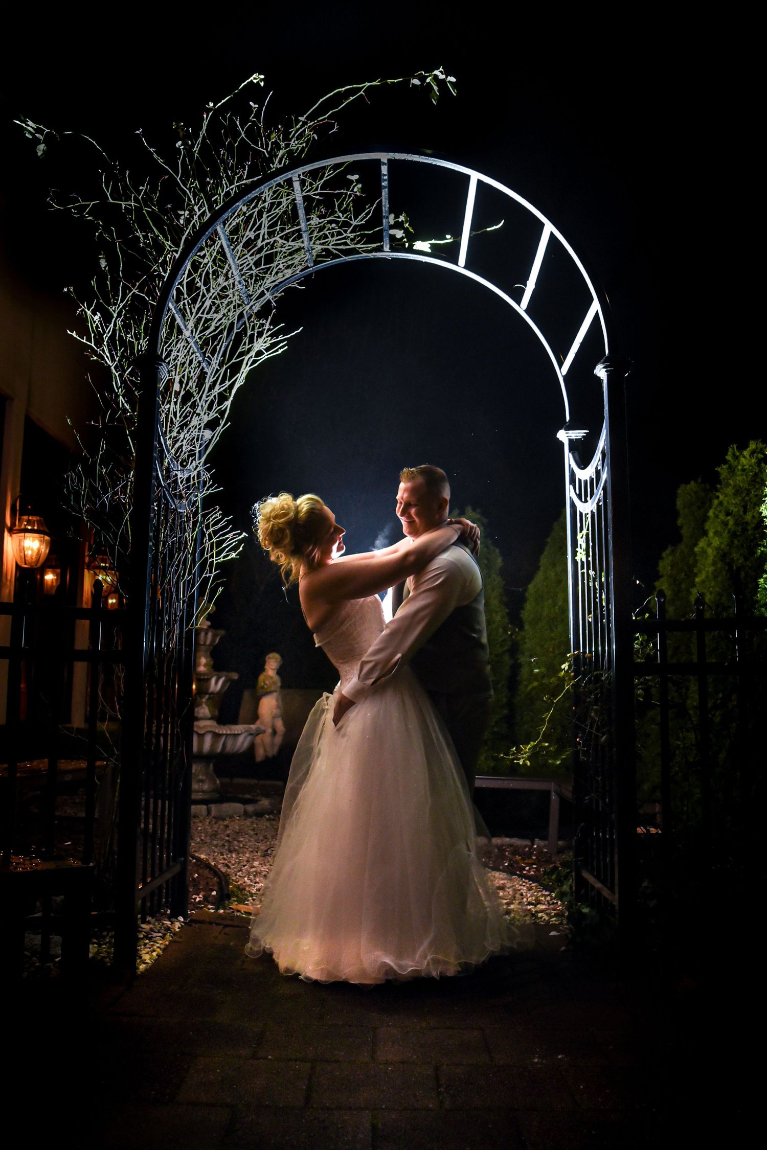 Romantic nighttime dance under illuminated garden archway.