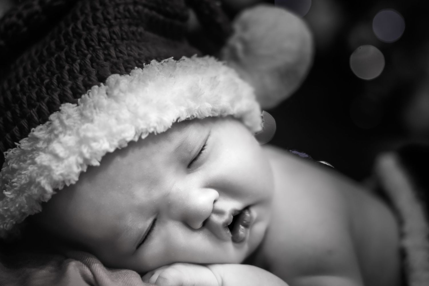 A black and white montage of intimate newborn baby photos showing tiny hands, feet, and sleeping poses.