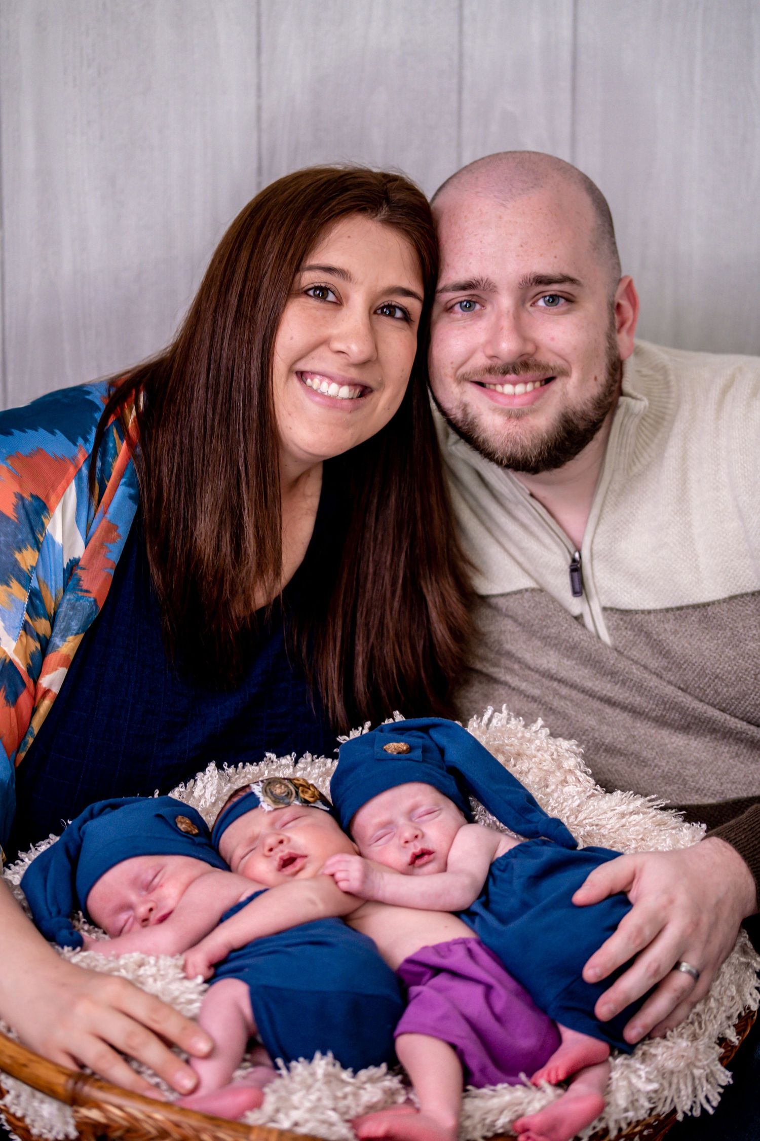 A couple smiles while holding two sleeping infants wearing blue and purple outfits in a series of four photos.