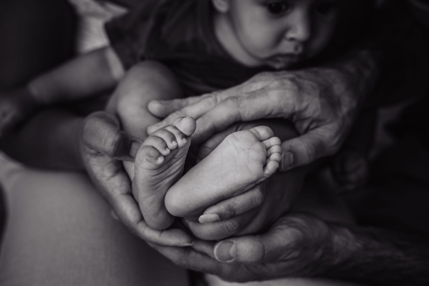 Black and white close-up photograph showing two hands gently clasped together in an intimate moment.