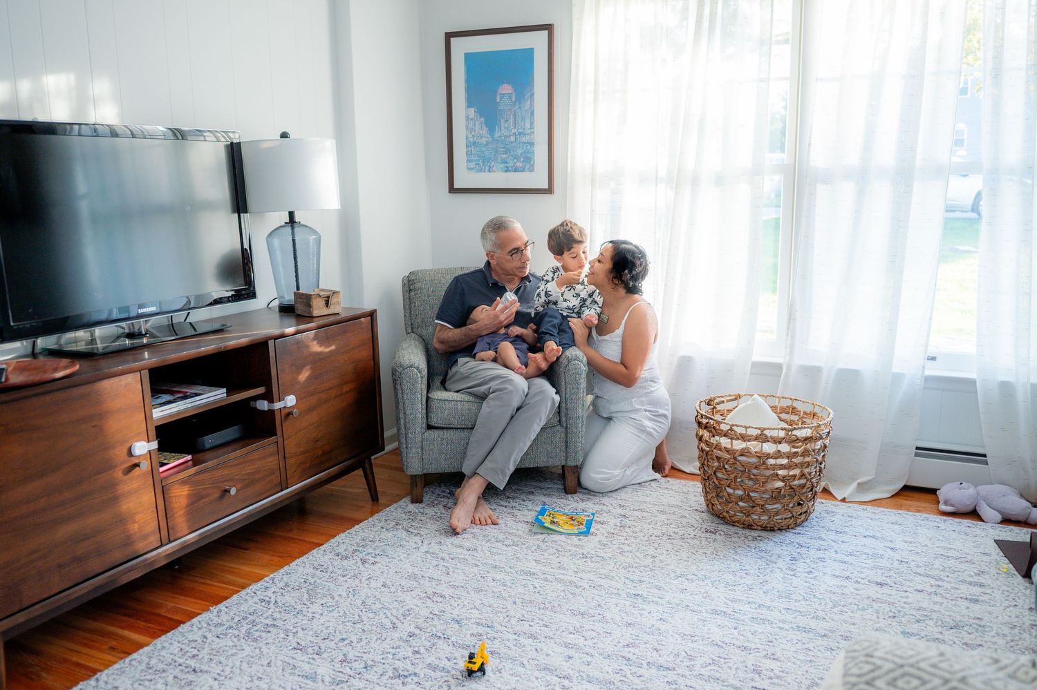A series of living room scenes showing a gray area rug, wooden TV stand, and family moments on the floor.