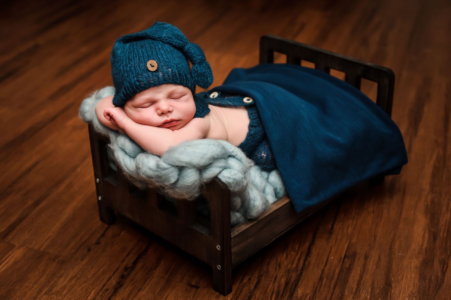 A sleeping newborn baby wrapped in soft white blankets rests peacefully in a vintage brown leather suitcase.
