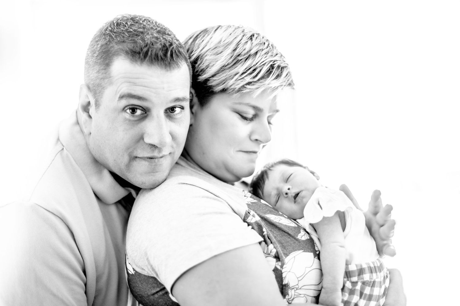 A black and white portrait of a couple holding their newborn baby in a tender family moment.