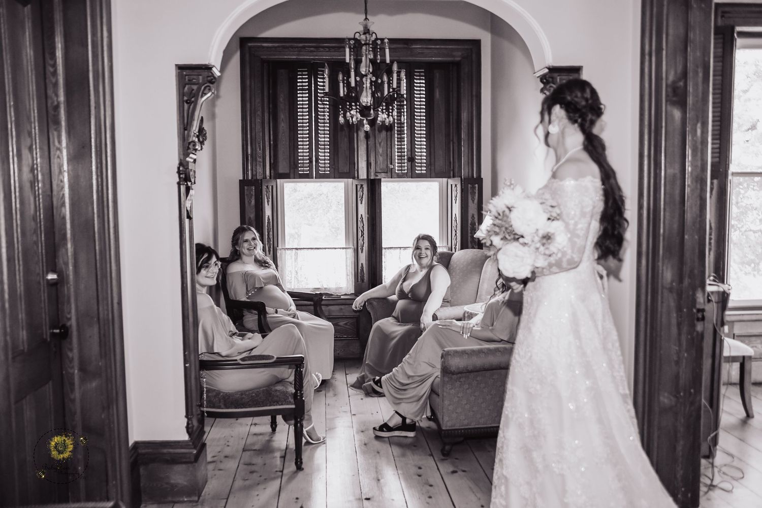 Black and white photo capturing pre-wedding moments in an elegant room with arched doorways.
