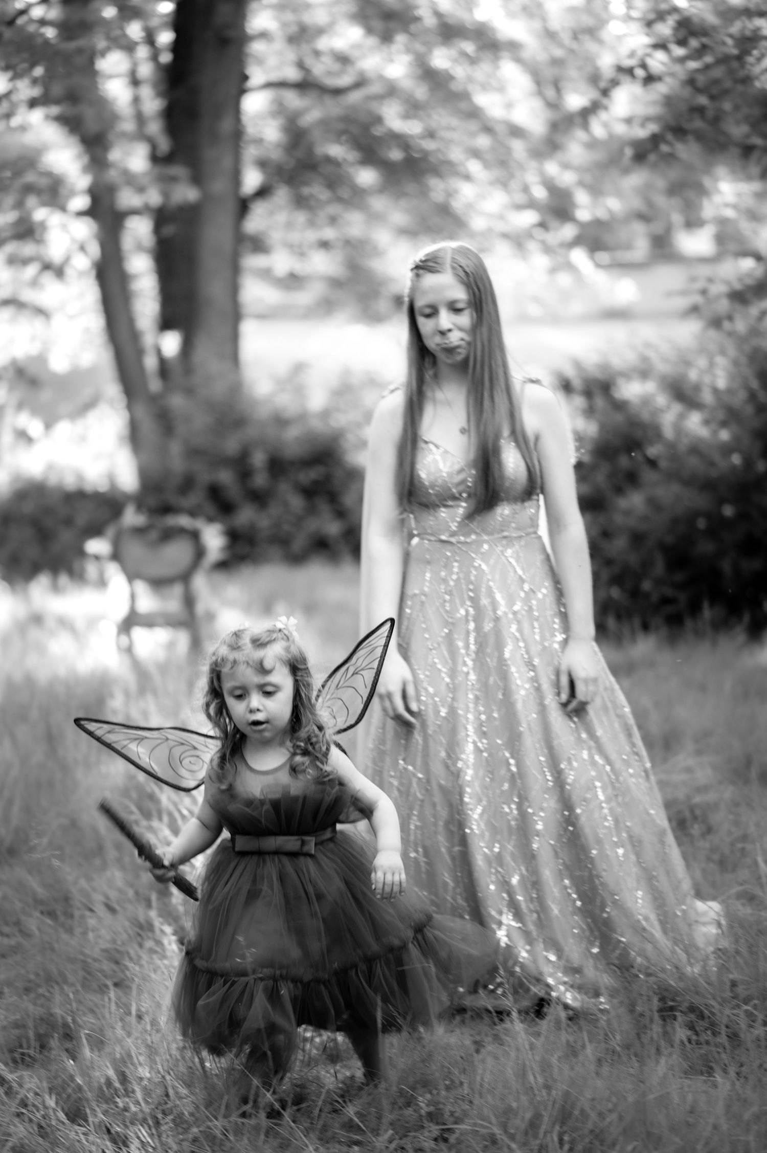 Black and white photo series of a magical fairy-themed outdoor portrait session in a grassy meadow.