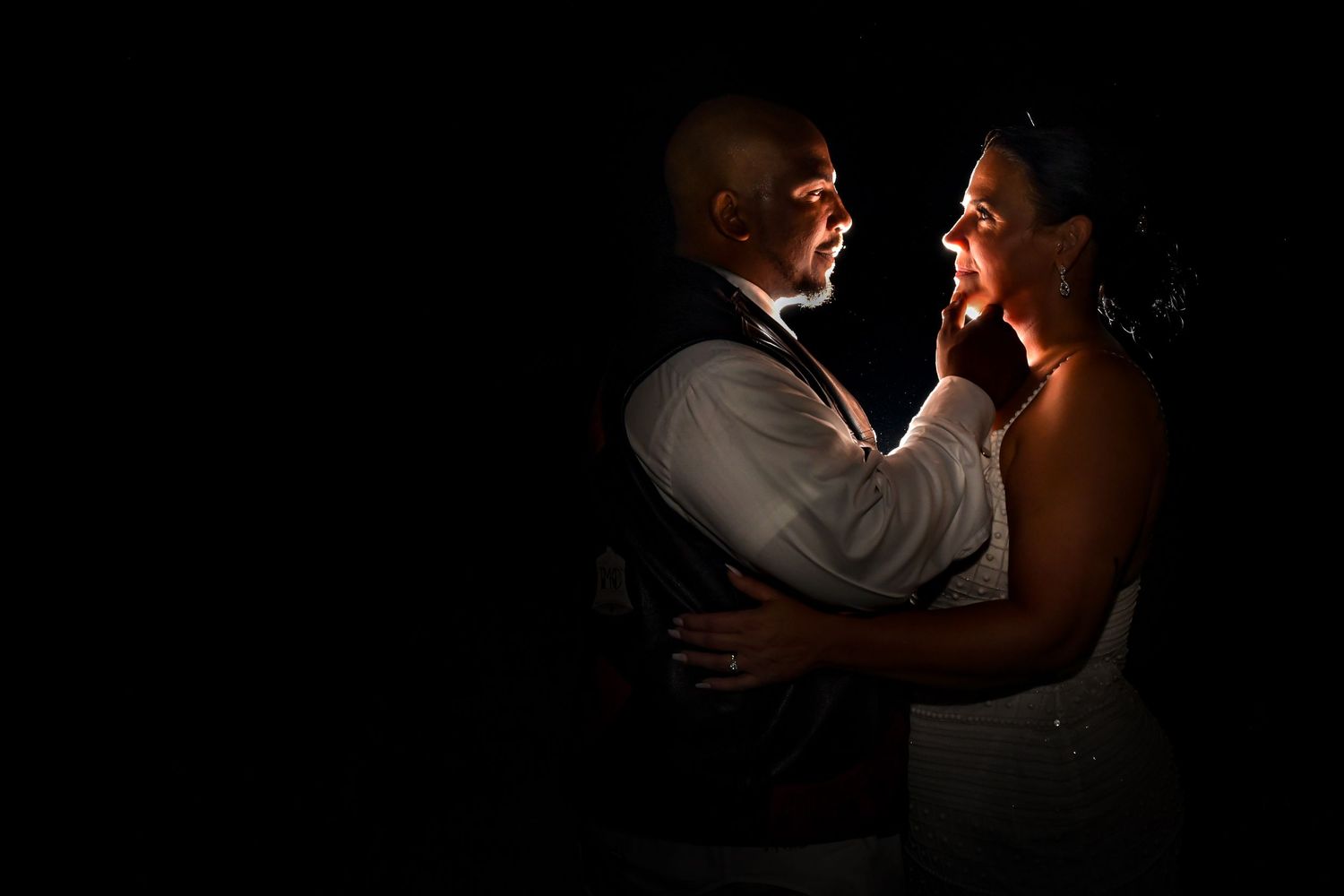 Romantic silhouette of couple dancing in dark room with dramatic lighting.