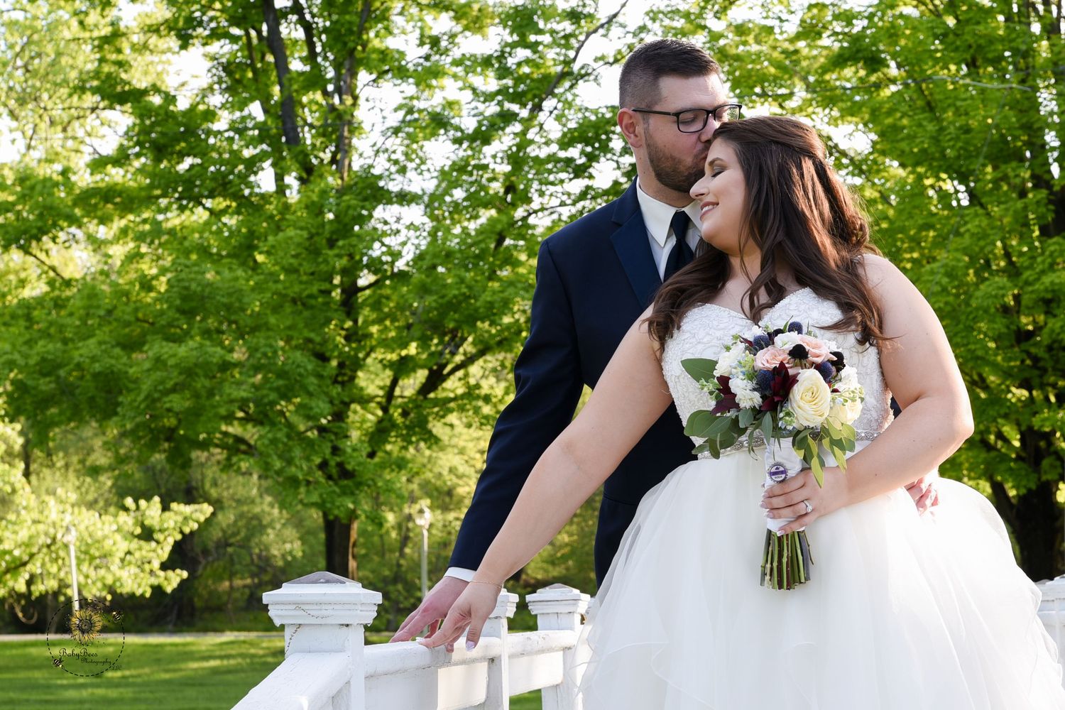 A romantic wedding moment captured in a lush garden setting with white floral bouquet.