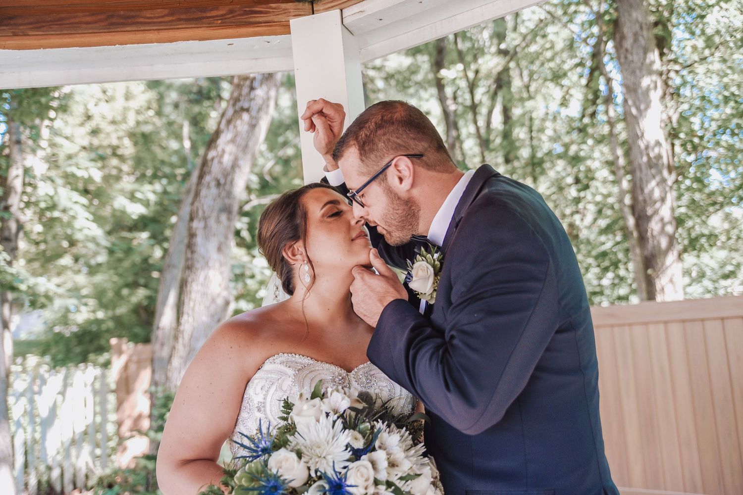 Romantic outdoor wedding portraits under wooden beams and natural lighting.