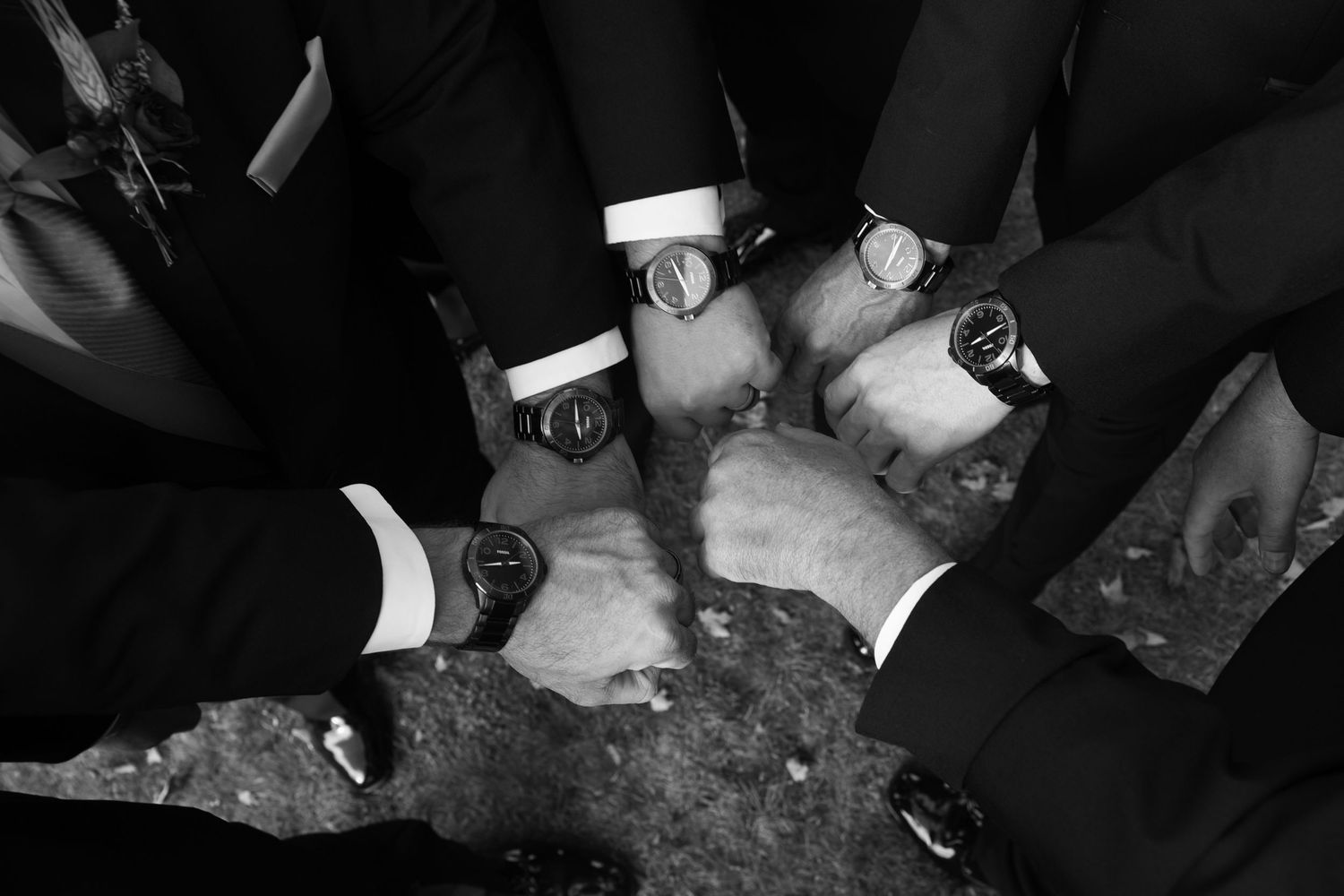 Wedding party members in formal attire gather for candid black and white photo.