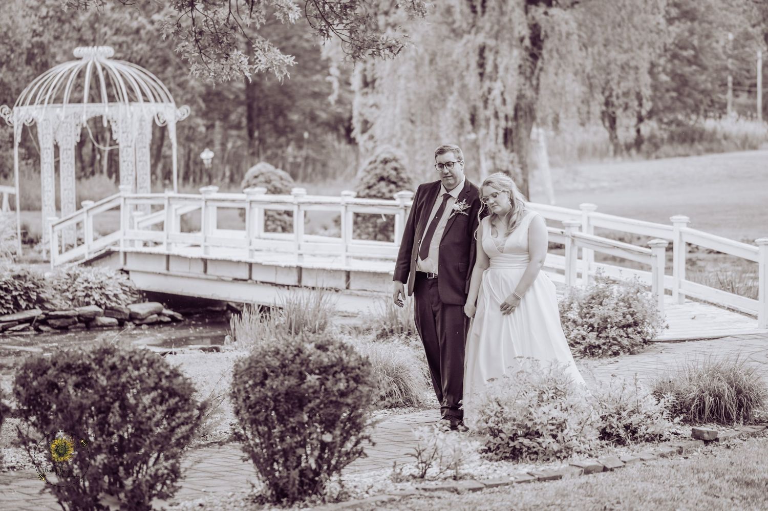 Garden wedding venue with white gazebo and landscaped grounds in black and white.