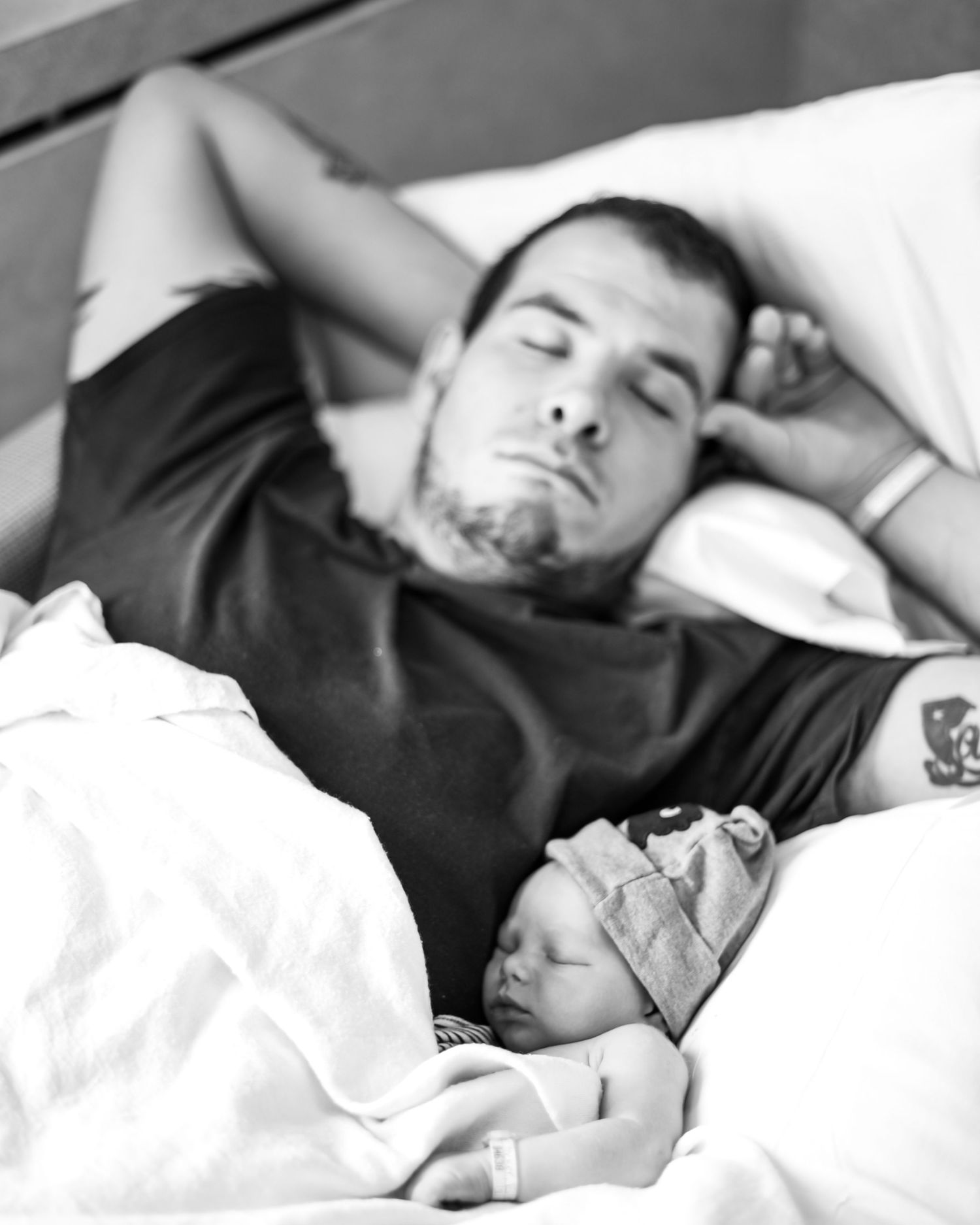 A couple sleeping peacefully together in bed, shown in black and white.