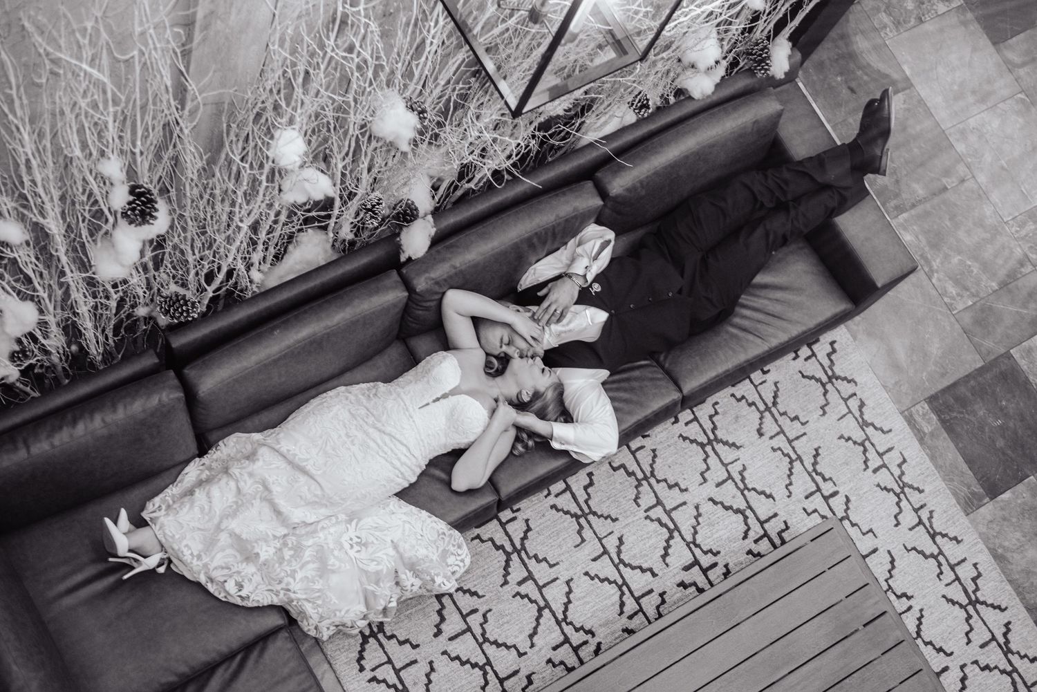 An overhead black and white view of a couple lounging on a patterned couch.