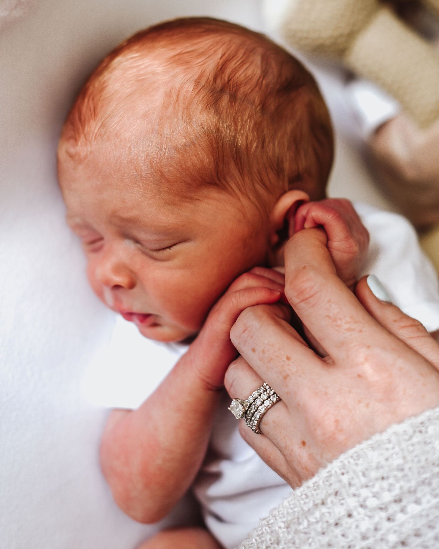 Close-up series showing gentle hands cradling a sleeping newborn baby in white blankets.