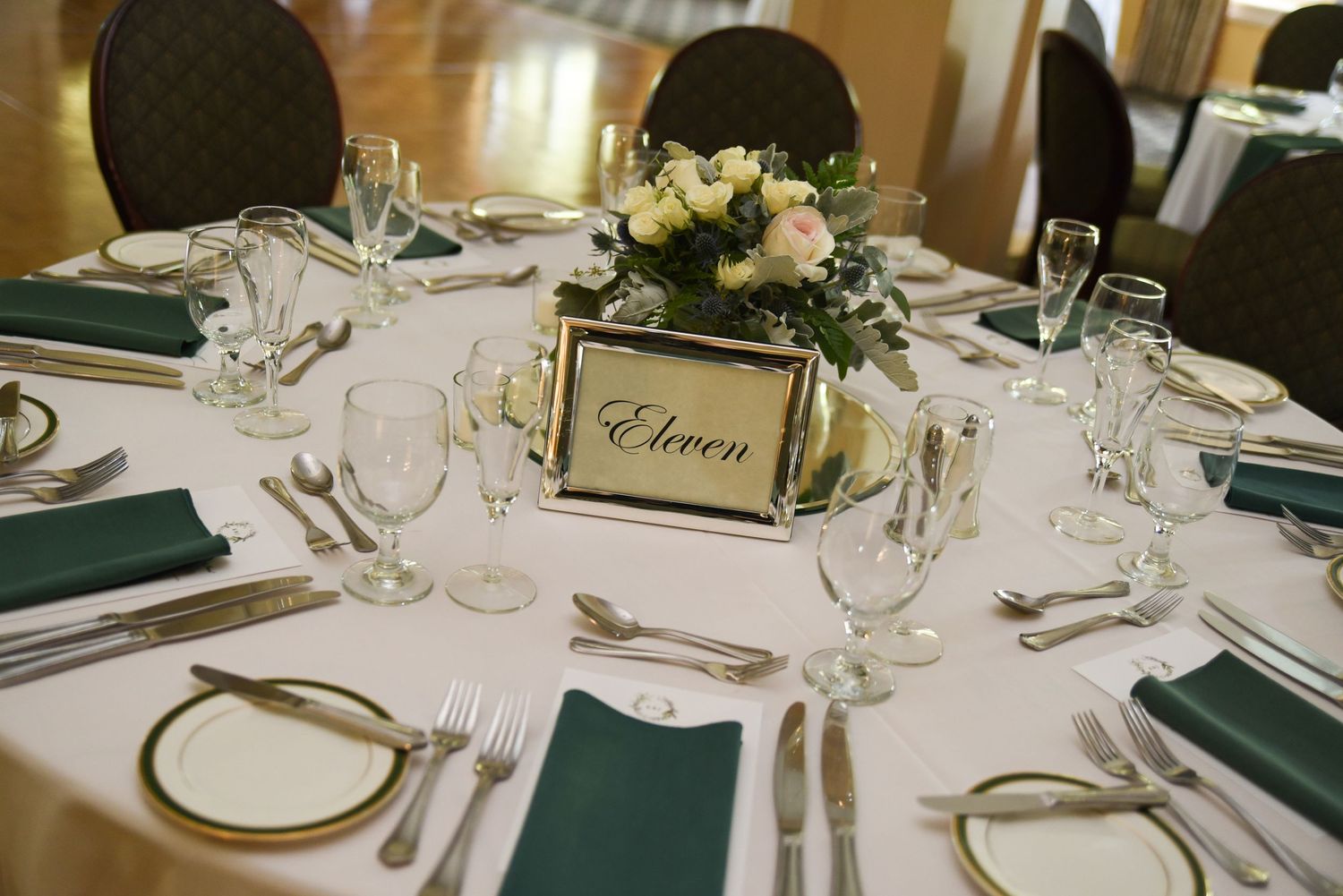 Elegant wedding reception table setting with white linens, wine glasses, and place cards.