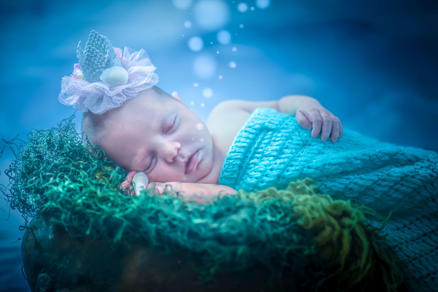 Ethereal underwater-themed newborn photography series with teal and blue tones creating a dreamy aquatic atmosphere.
