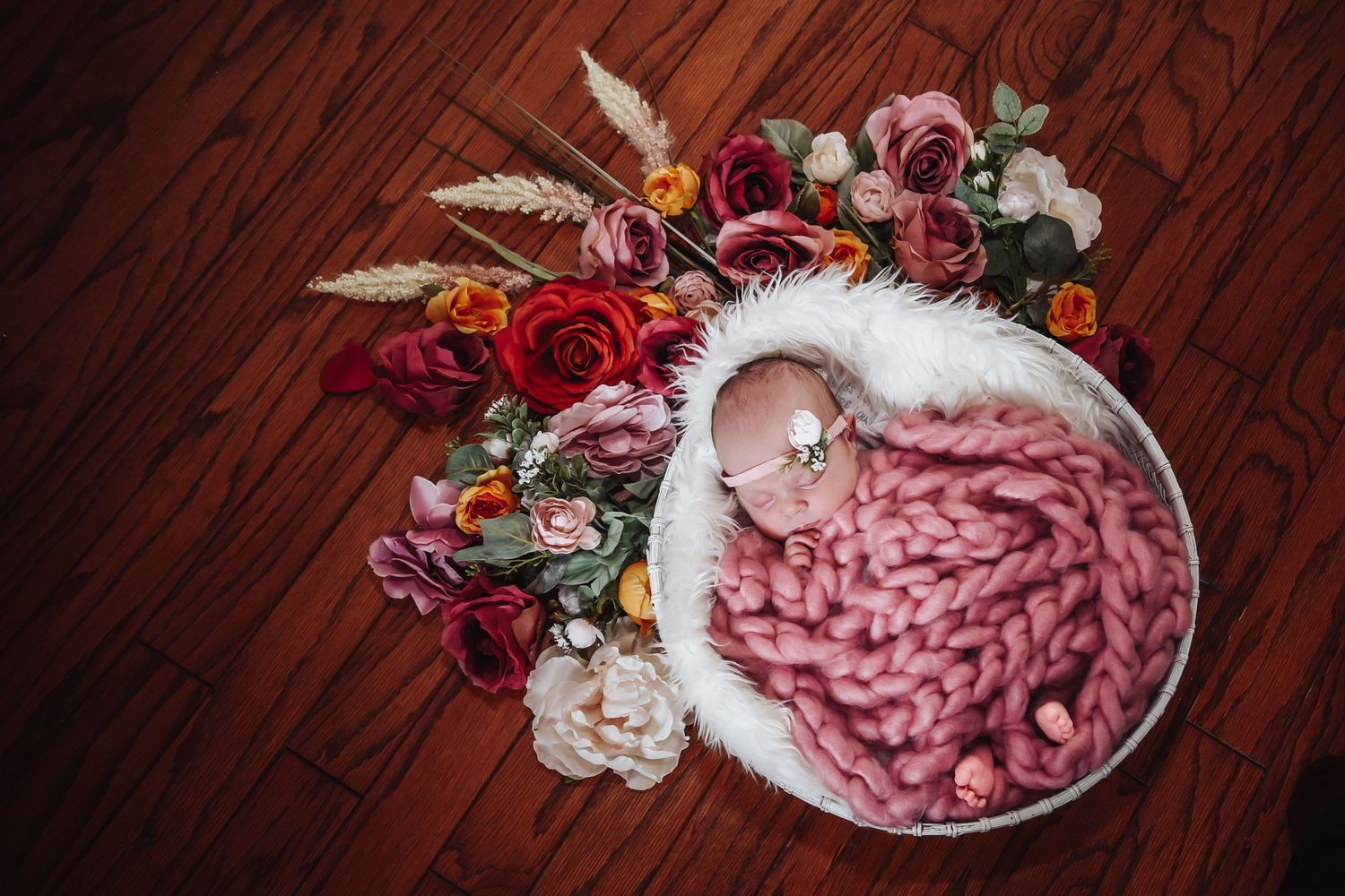 Overhead view of pink charcuterie meat slices arranged on white ceramic plate with floral decorations on wooden table.