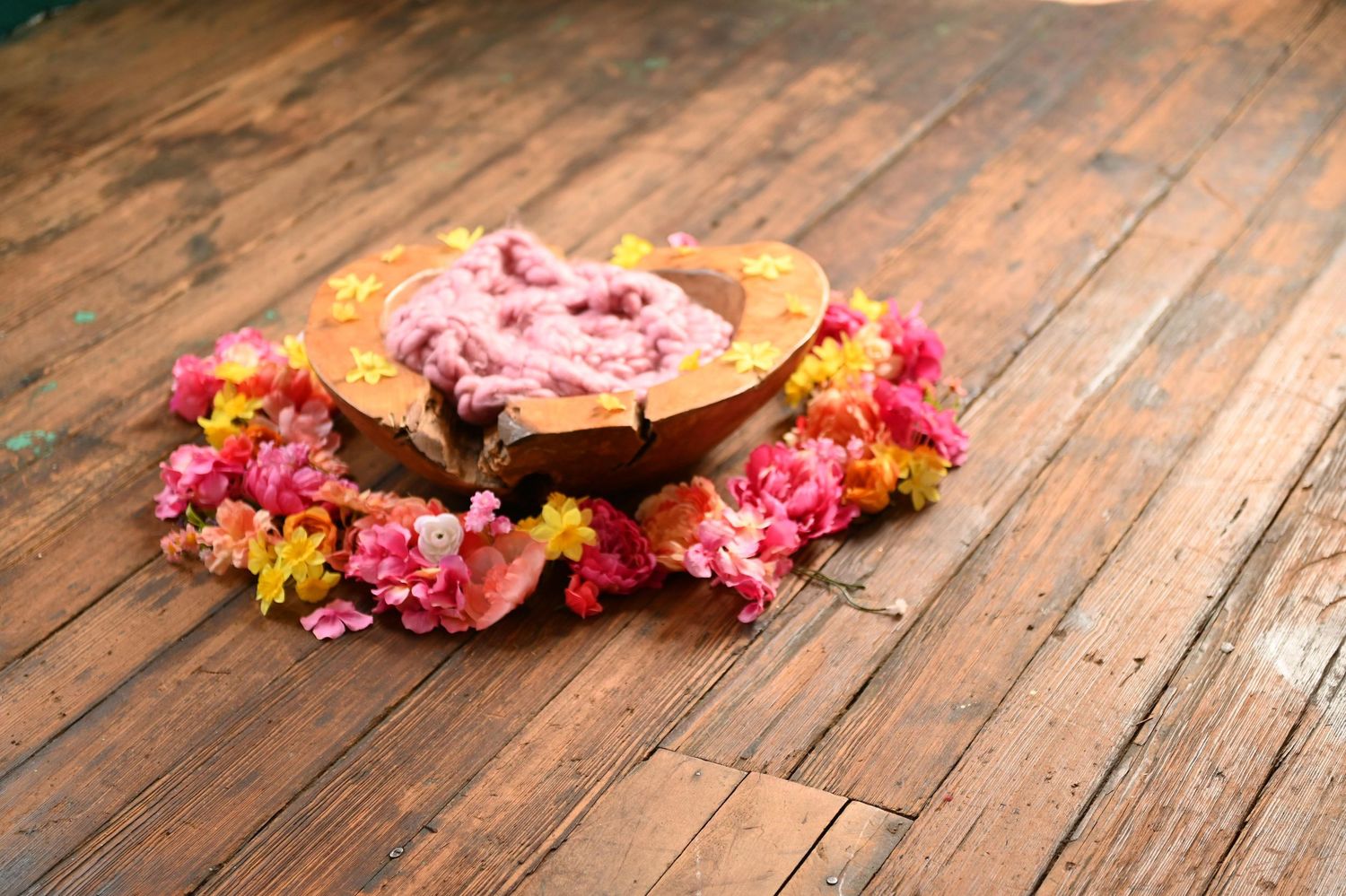 Pink and yellow flower petals scattered on rustic wooden floorboards create a decorative pattern.