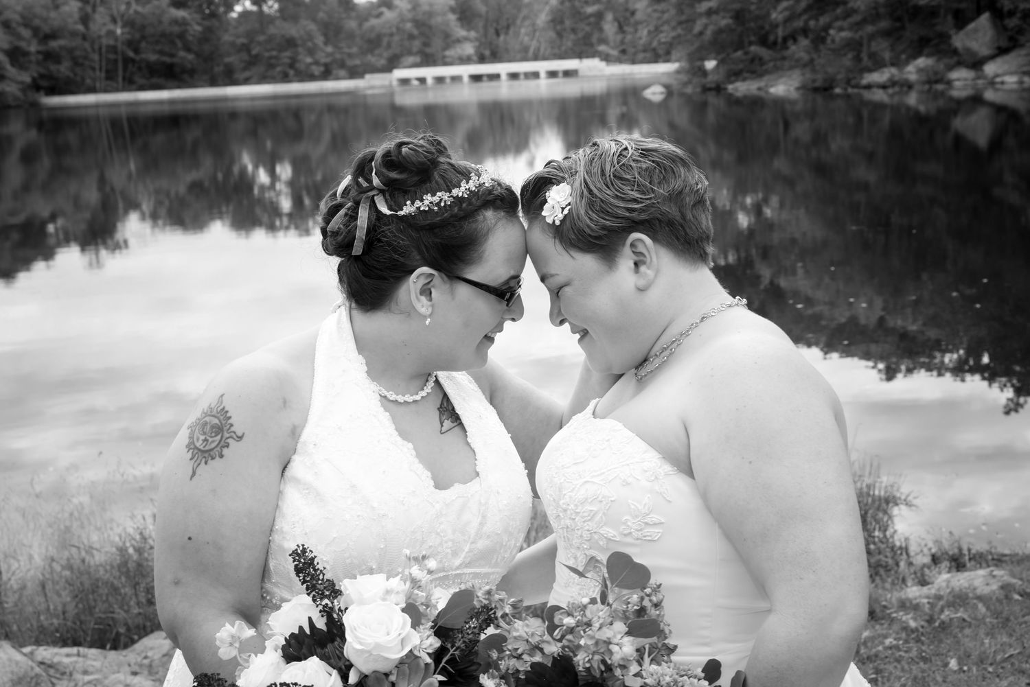 A romantic black and white wedding photo series showing intimate moments between newlyweds by a lake.