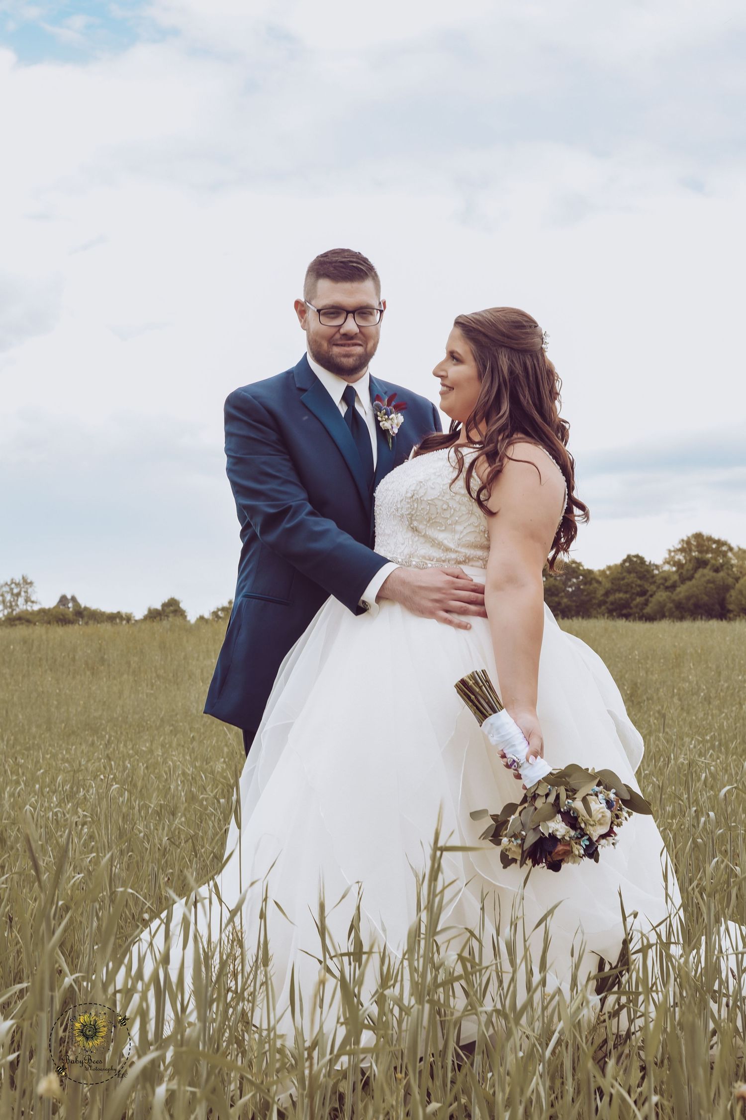 Romantic wedding portrait of couple standing together in a meadow.