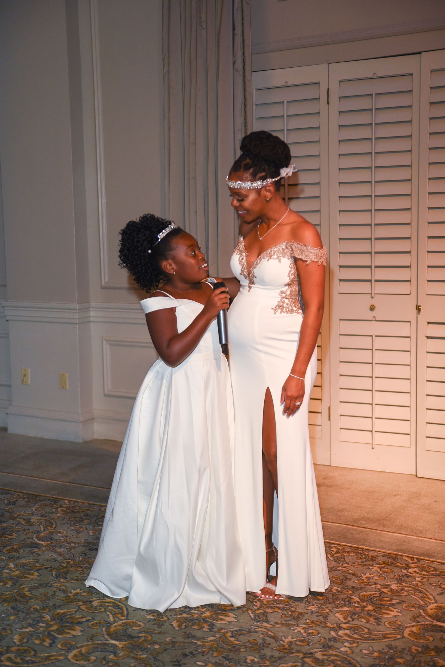 Two people in white dresses share an intimate moment during a wedding ceremony.
