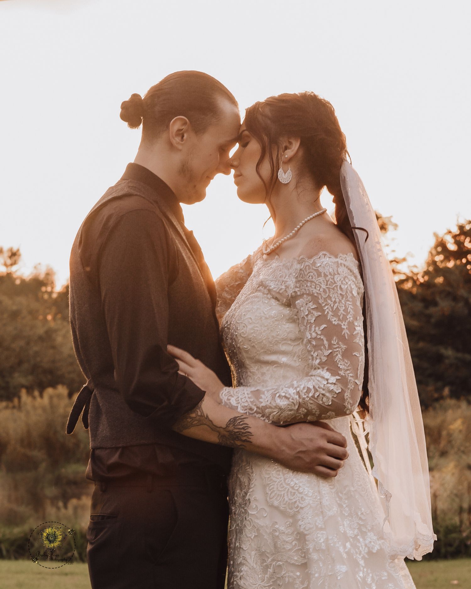 A romantic sunset portrait of a couple in wedding attire embracing in warm light.