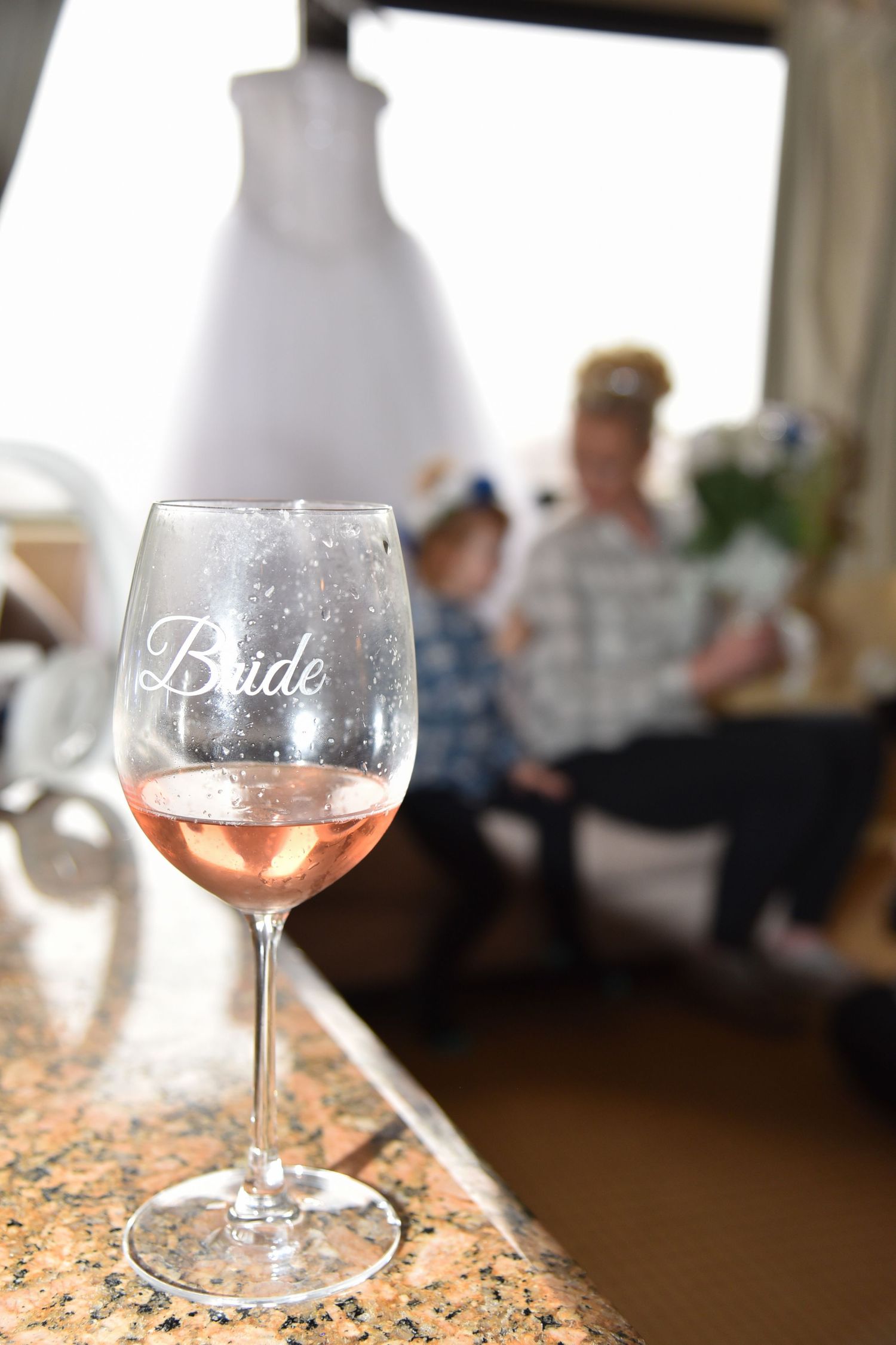 Wedding reception details with engraved wine glasses on granite countertop.