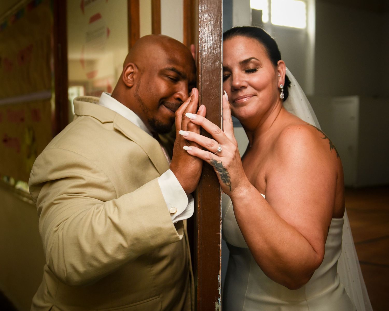 Intimate moment between couple on opposite sides of door during first look wedding photo.