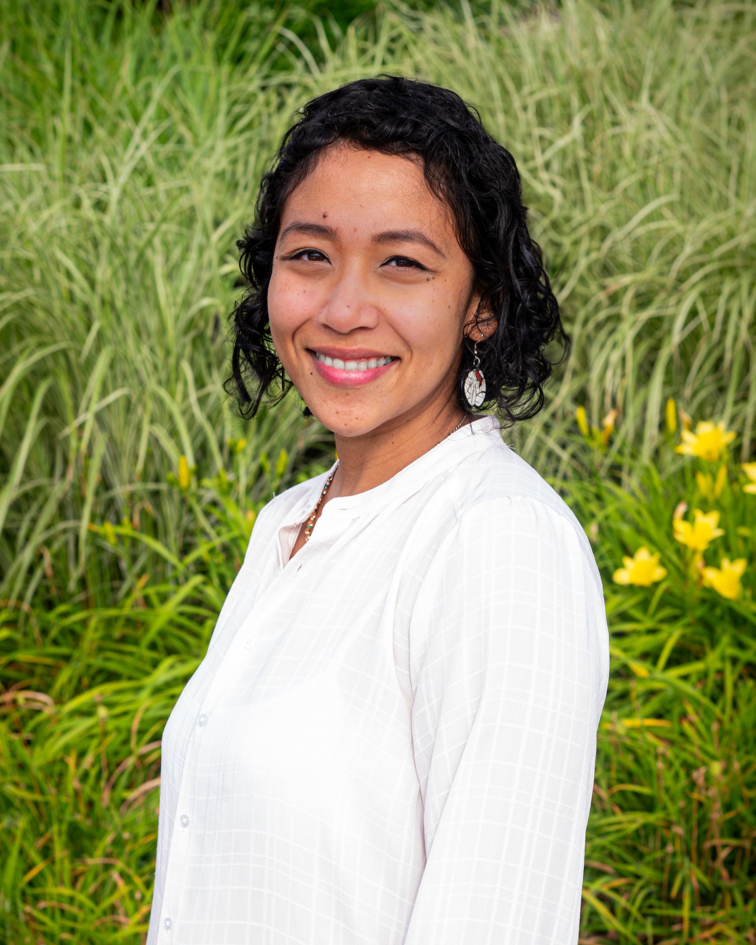 A person in a white top poses against a green grassy background with yellow flowers in a series of outdoor portraits.