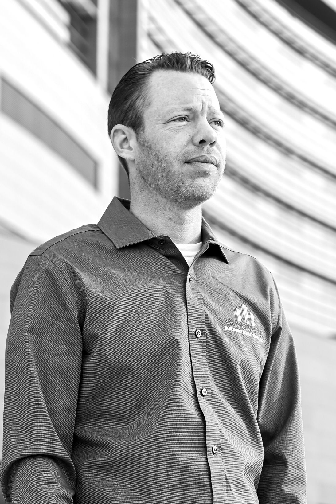 A black and white profile portrait showing a person in business attire looking to the side against a curved wall.