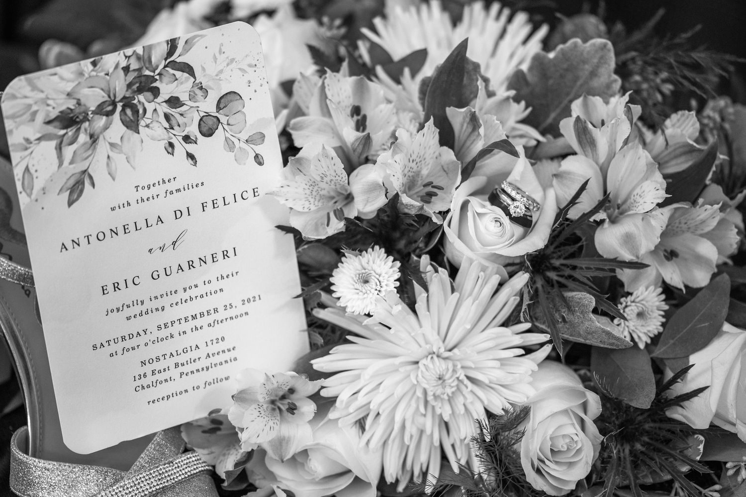 Black and white close-up of wedding flowers and invitation details.